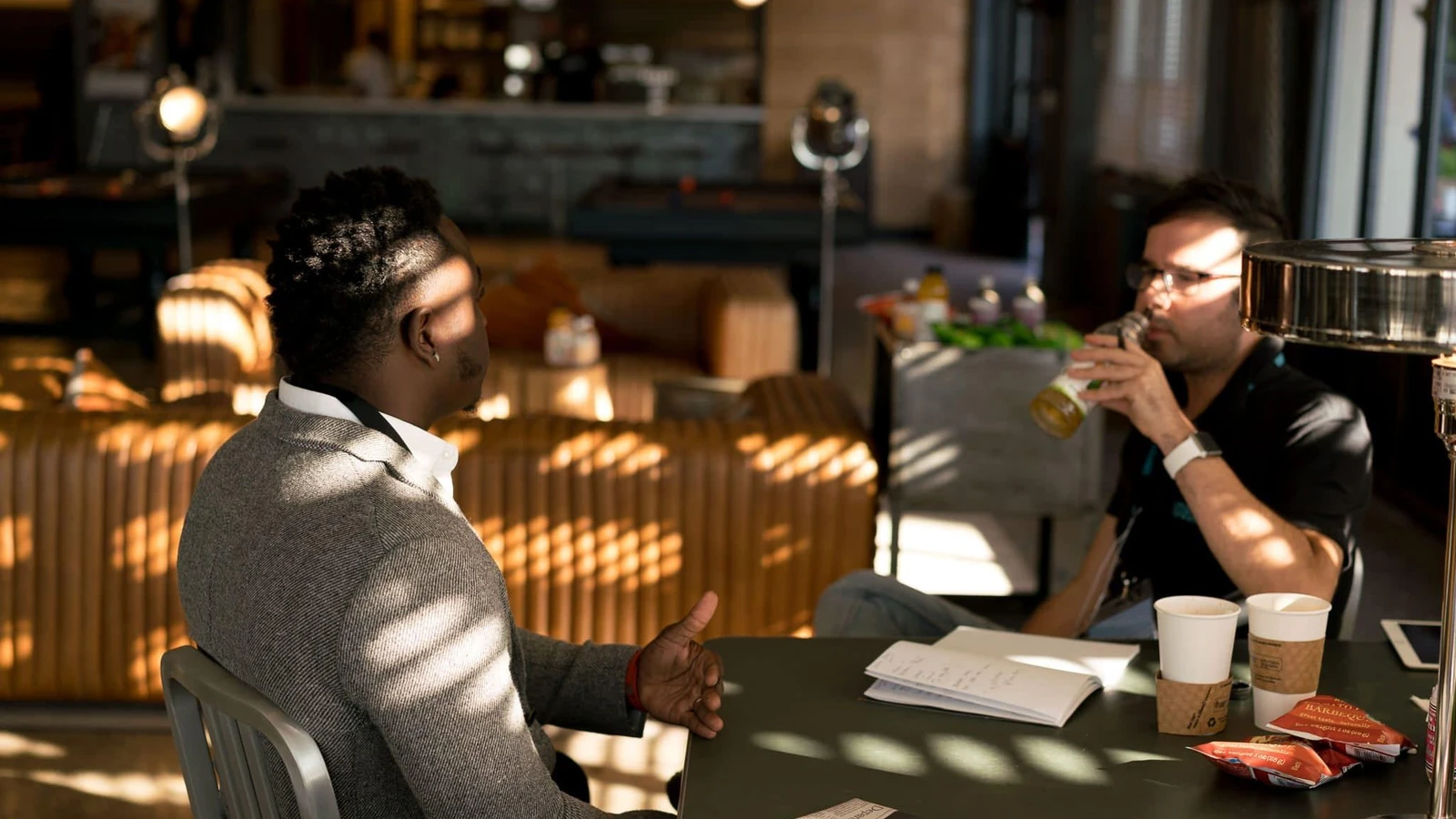 Due adulti che hanno un incontro informale con bevande in un ambiente moderno interno.