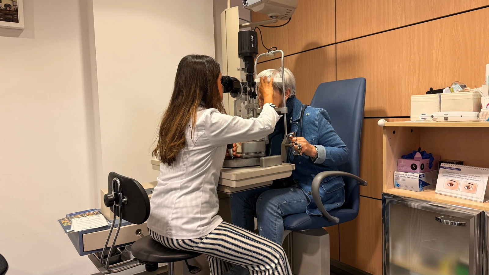 Un optometrista esegue un esame della vista con una lampada a fessura in una sala visite ben illuminata.