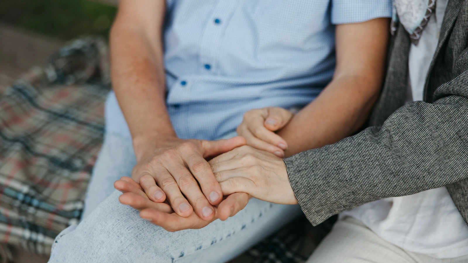 Un primo piano di una coppia che si tiene per mano, simboleggiando amore e unione.
