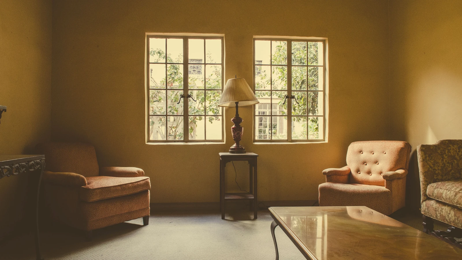 Un interno vintage del soggiorno con poltrone e una lampada, immerso nella calda luce naturale.