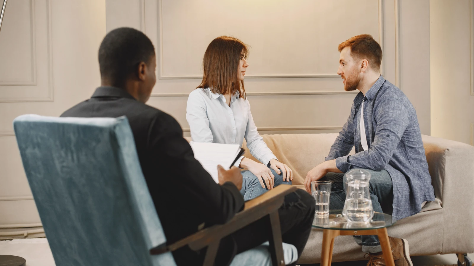 Coppia in una sessione di consulenza con un terapeuta in un ambiente moderno e accogliente.