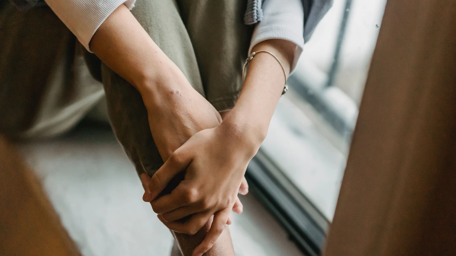 Una donna seduta vicino a una finestra, immersa nei suoi pensieri, simbolo di pace e solitudine.