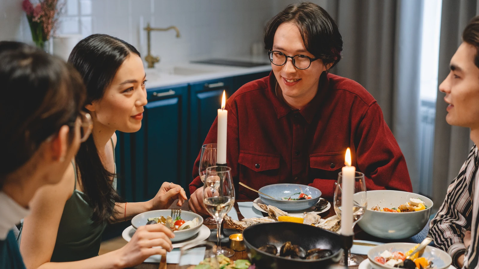 Un gruppo di adulti asiatici che cena a lume di candela, condividendo cibo e conversazione.