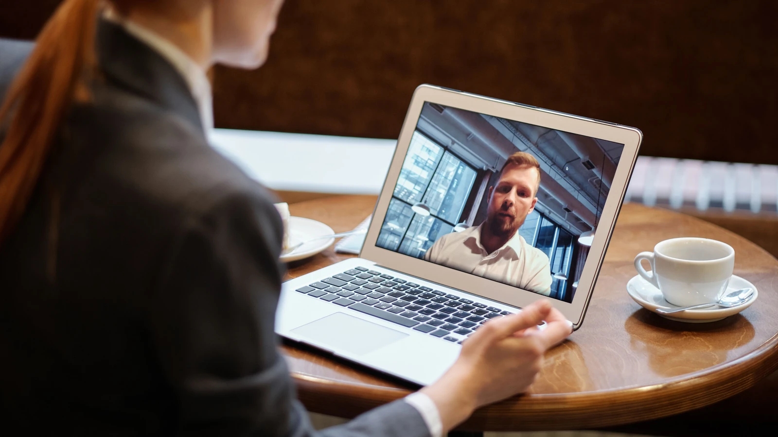 Una donna d'affari in un caffè che utilizza un laptop per una chiamata di videoconferenza online.