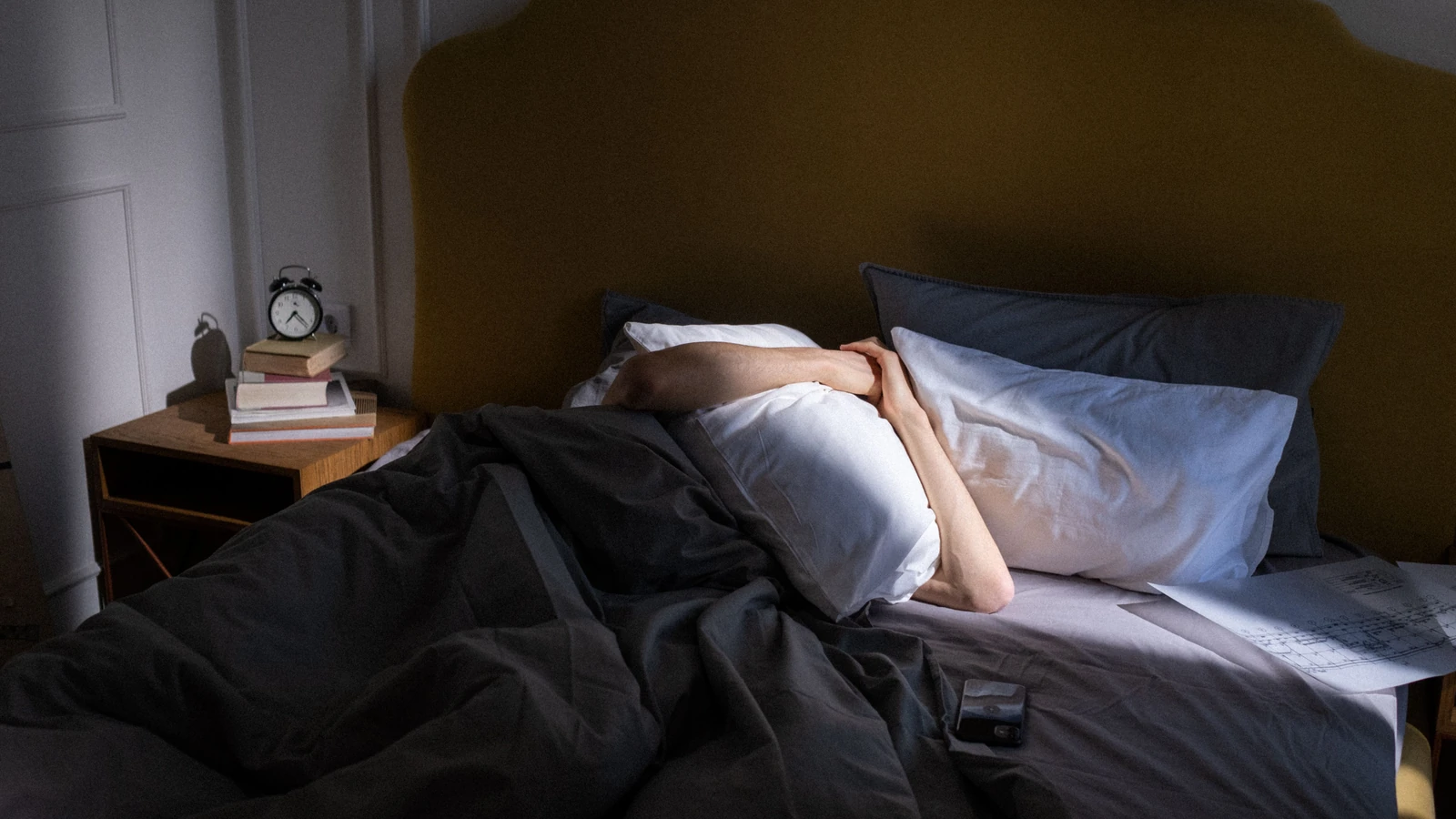 Una camera da letto tranquilla con una persona che riposa alla luce del sole, che cattura un'atmosfera serena di prima mattina.