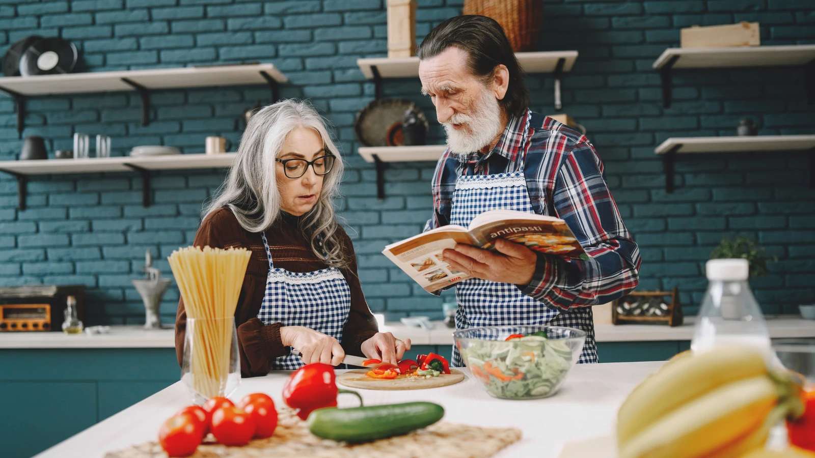 Coppia anziana che prepara un pasto insieme in una cucina elegante, enfatizzando il legame e il lavoro di squadra.