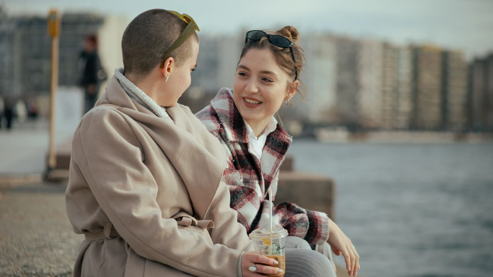 Due donne che godono di una conversazione al mare con un caffè. Un momento gioioso e rilassato.