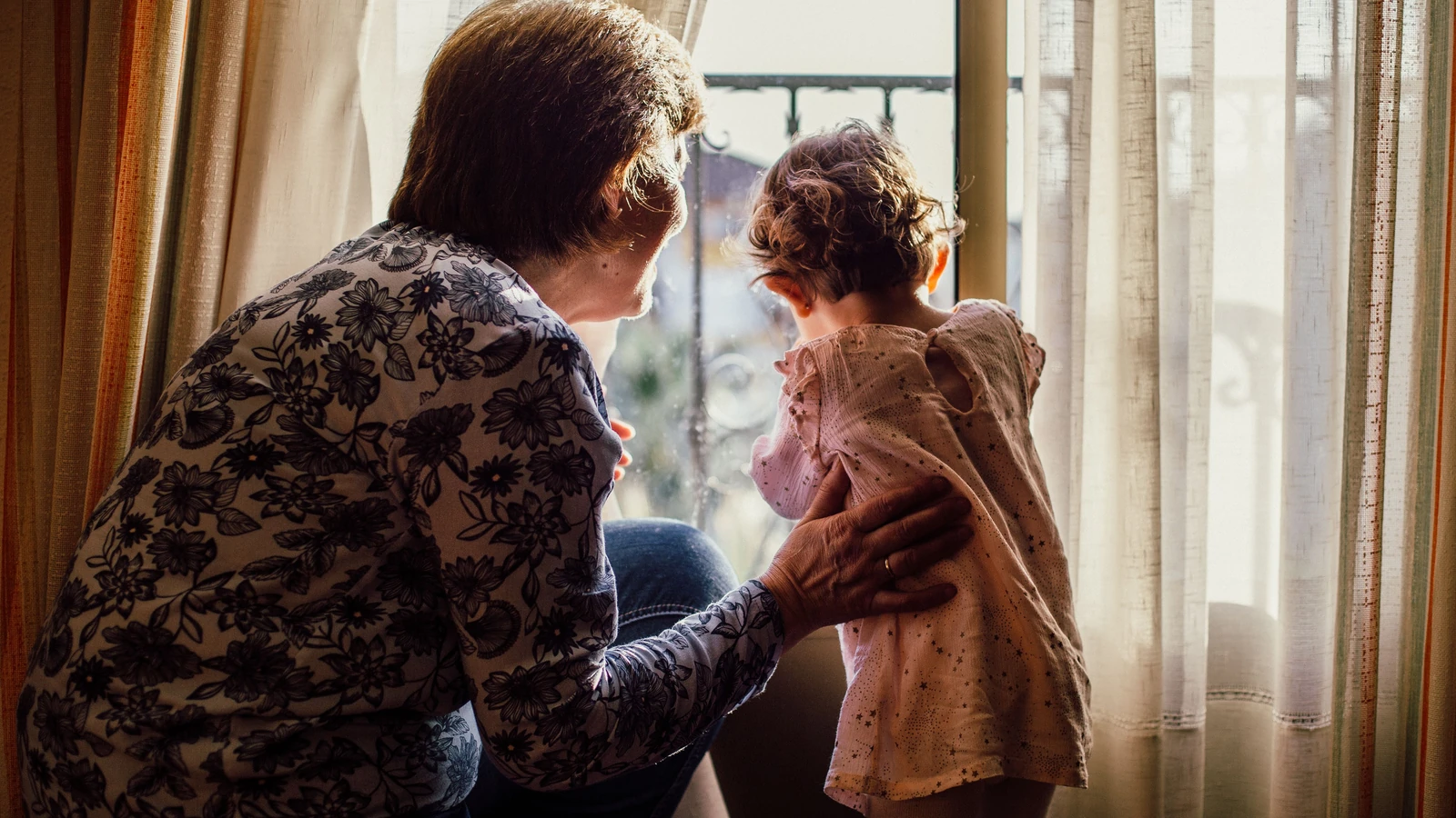Un momento d'amore tra nonna e nipote vicino a una finestra piena di luce solare.