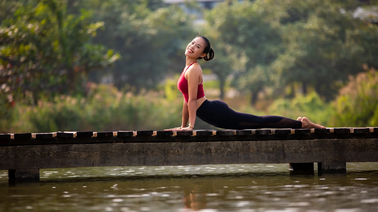 Una donna pratica yoga su un ponte, mostrando flessibilità e serenità in un ambiente naturale.
