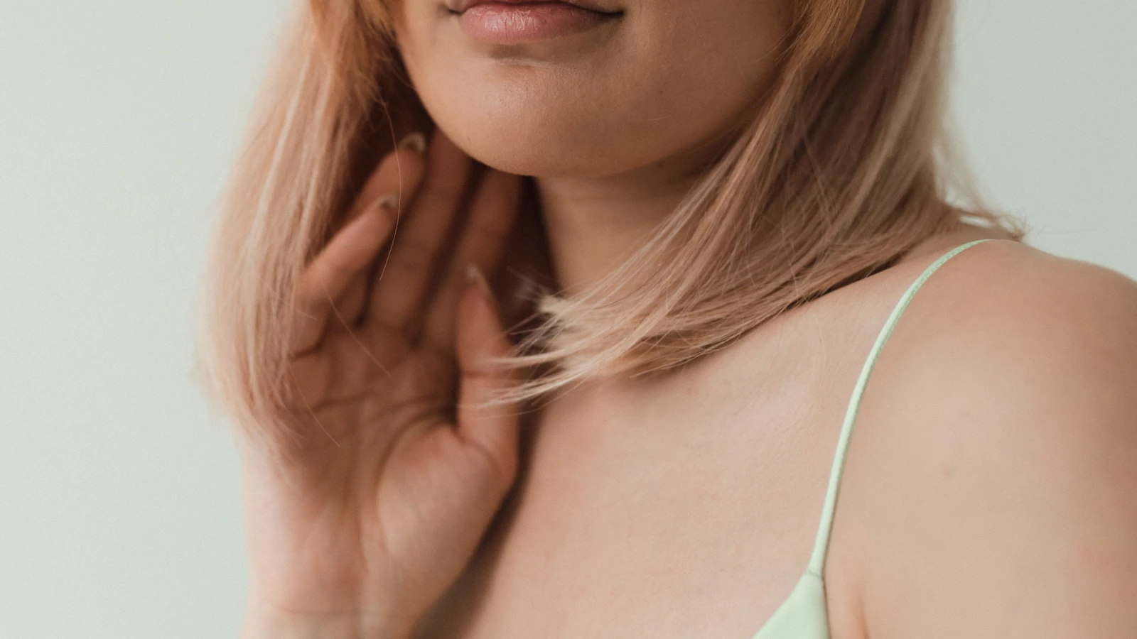 Primo piano di una donna con capelli biondi e top a spaghetti, che mette in risalto la bellezza dolce e naturale.