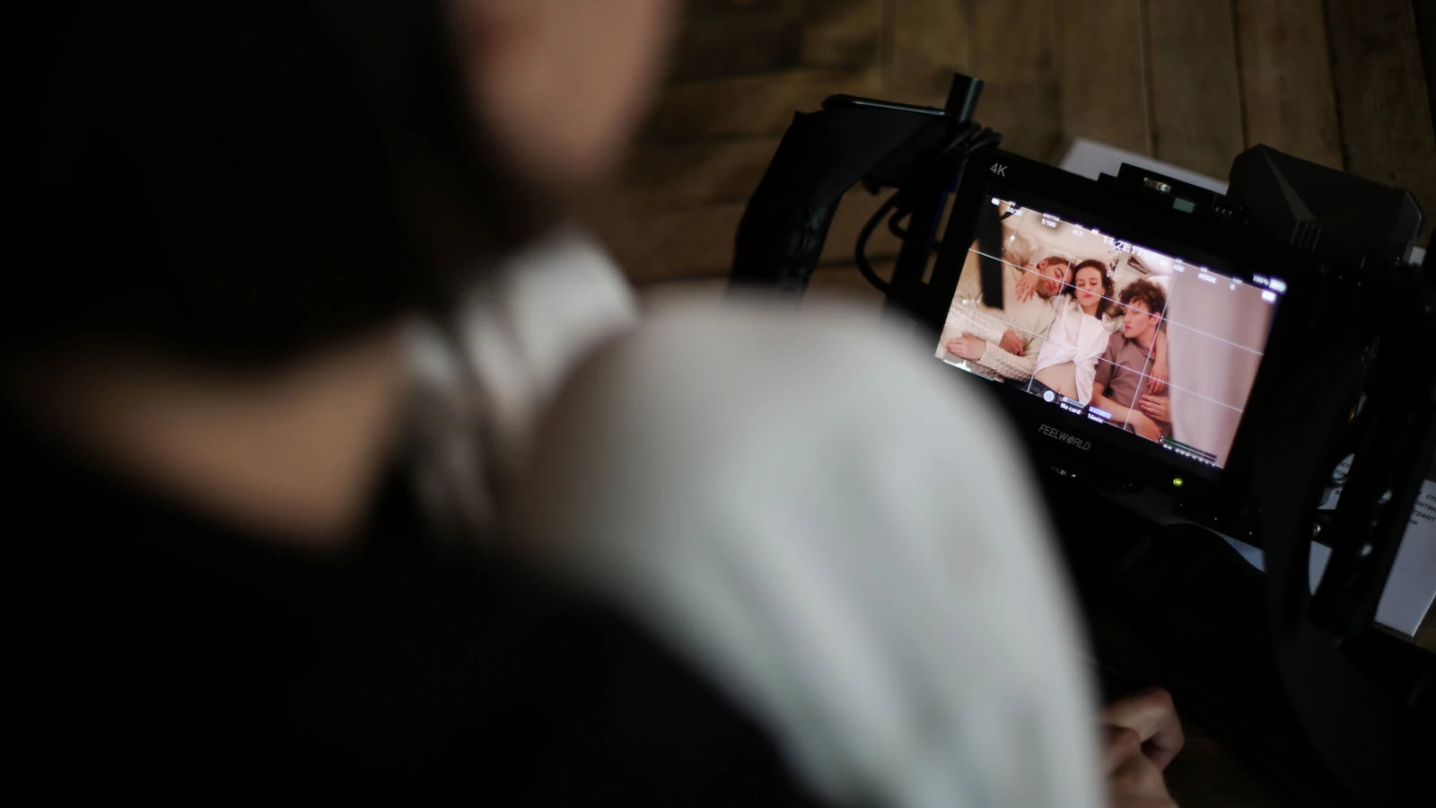 Un membro della troupe cinematografica rivede le riprese su un monitor, catturando uno sguardo dietro le quinte del processo creativo.