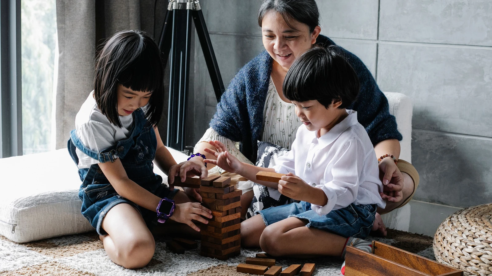 Una famiglia gioiosa che gioca insieme a un gioco di blocchi di legno al chiuso, migliorando i legami e il pensiero strategico. — Alex Green – Pexels