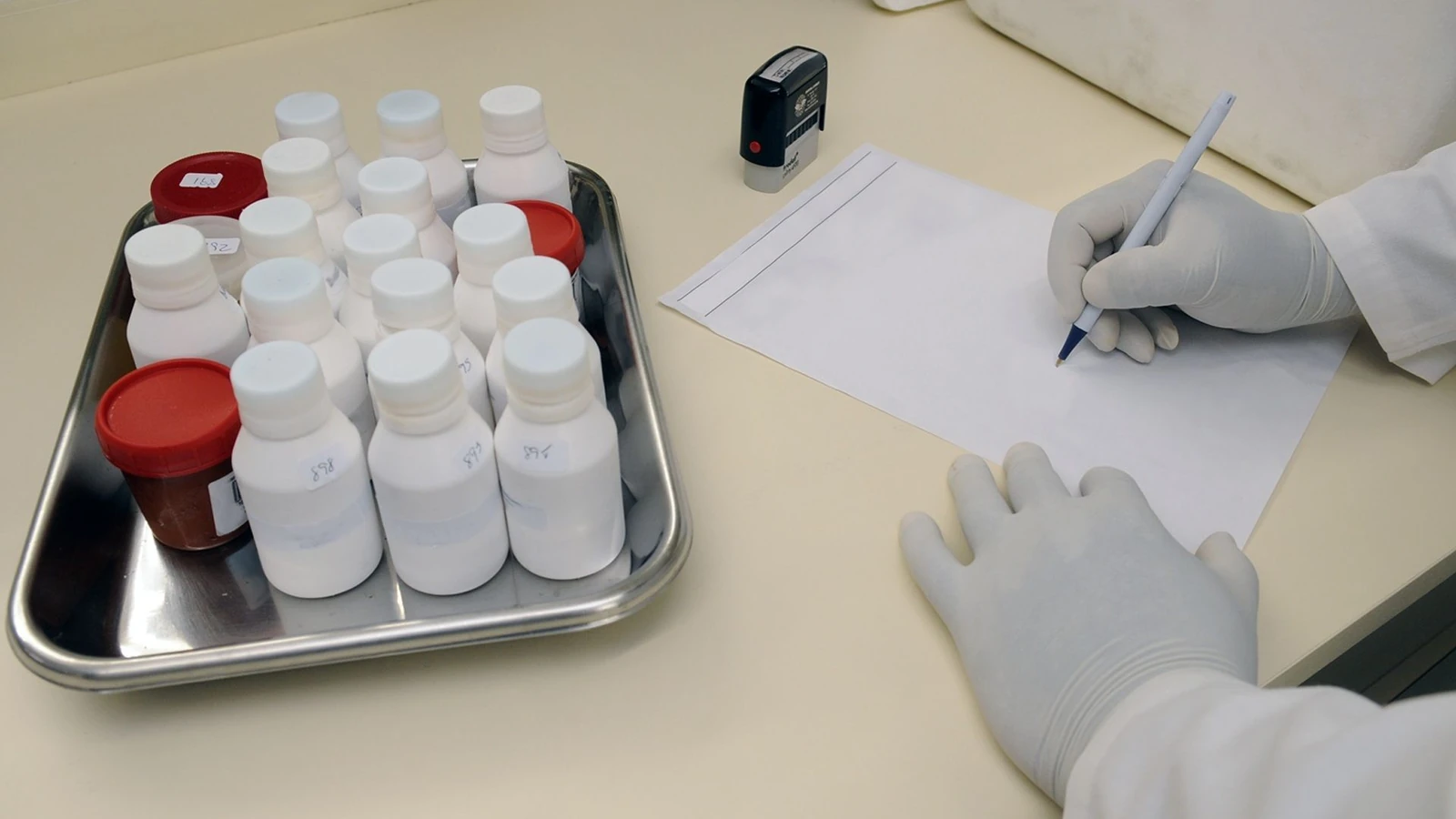 Tecnico di laboratorio che scrive rapporto con campioni in un laboratorio medico.