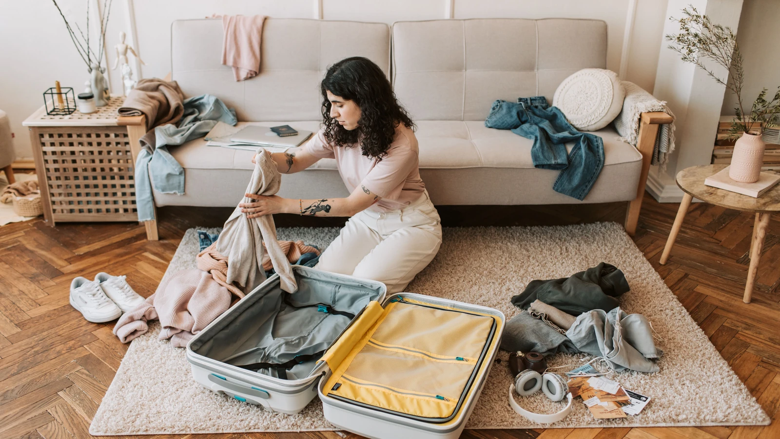 Donna che organizza i vestiti in una valigia mentre si prepara per un viaggio in un elegante soggiorno.