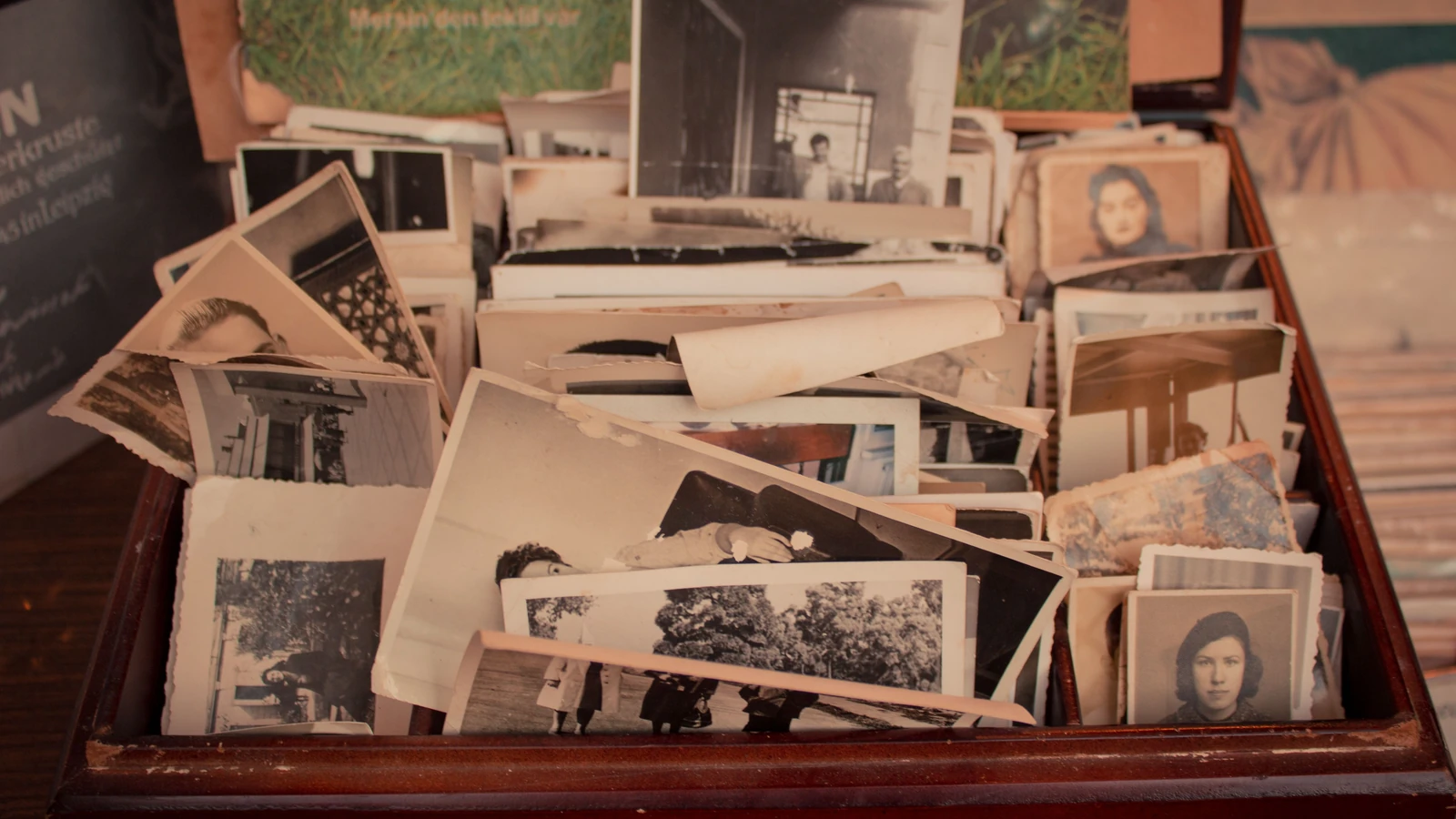 Una raccolta di vecchie fotografie in bianco e nero conservate in una scatola di legno vintage, che evoca nostalgia.