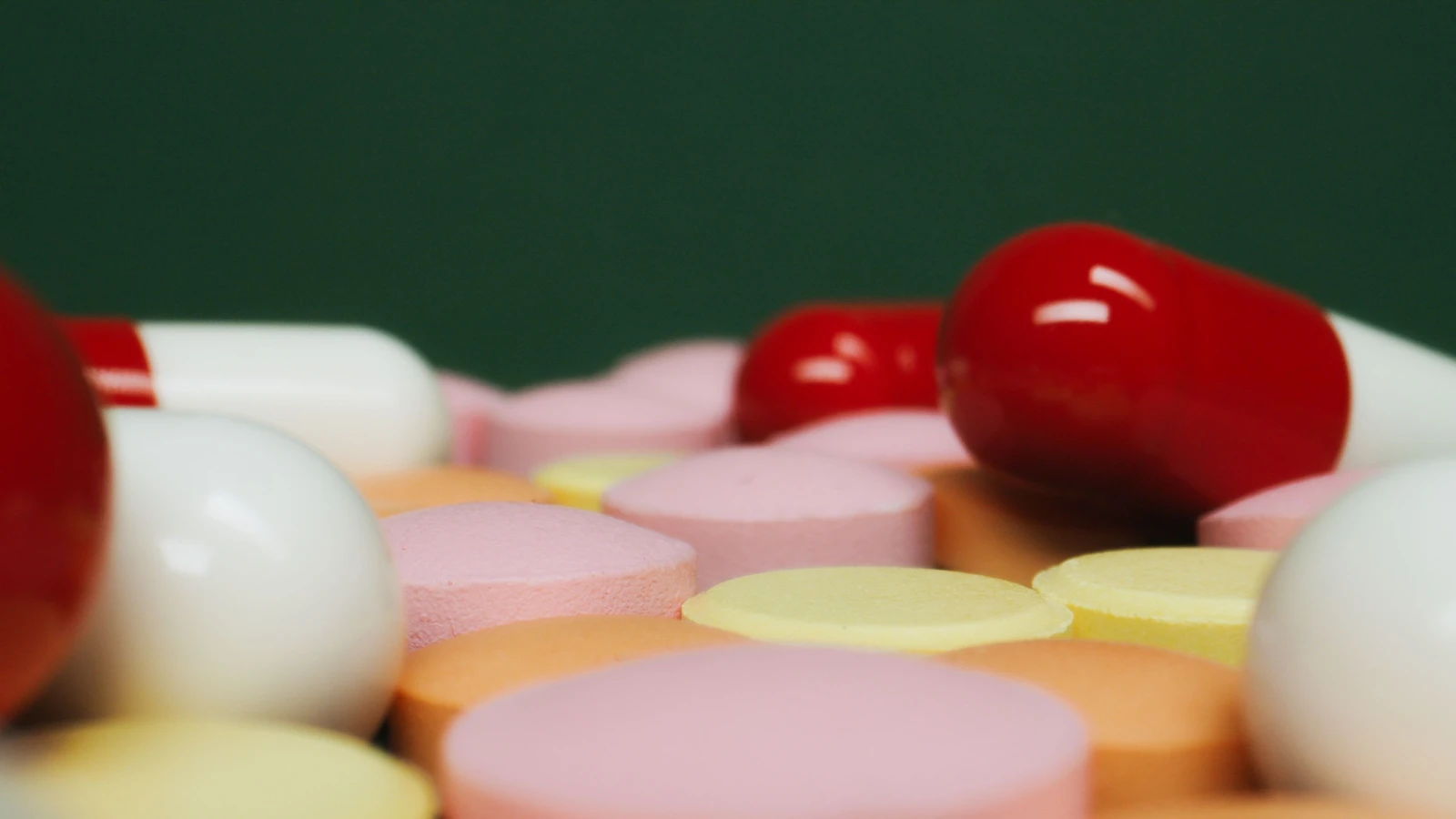 Una vista ravvicinata di varie pillole e compresse colorate su uno sfondo verde, con focus sulla varietà di farmaci. — Tima Miroshnichenko – Pexels