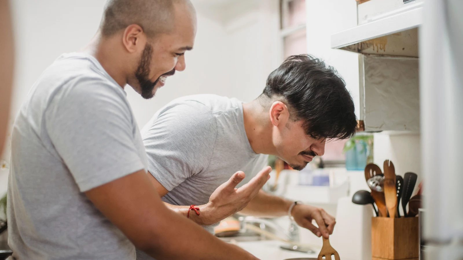 Una coppia gioiosa che ride e cucina insieme in una cucina luminosa. Perfetto per temi di lifestyle.