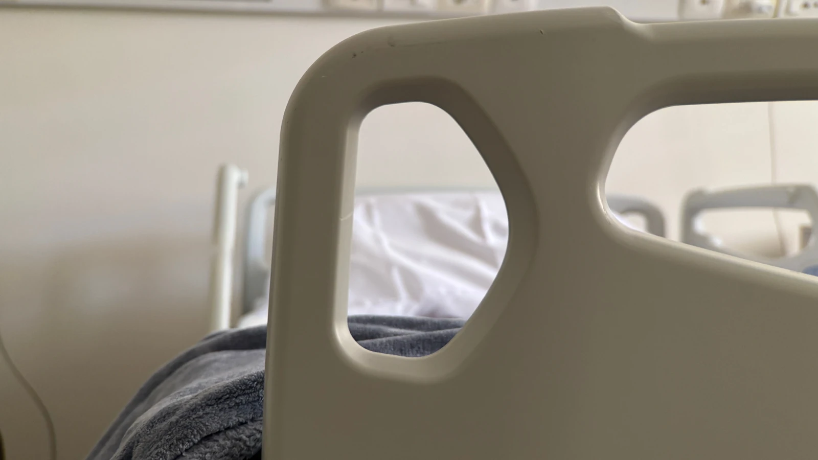 Primo piano della sponda di un letto d'ospedale vuoto in una stanza tranquilla.