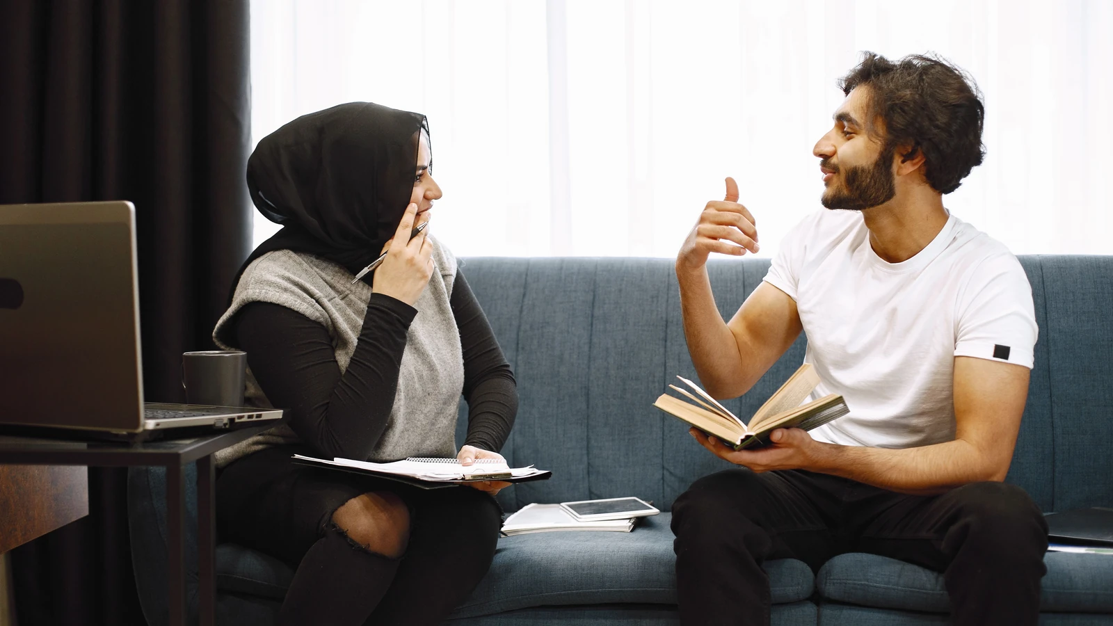 Un uomo e una donna che conversano calorosamente in casa, scambiandosi idee e sorridendo, creando un'atmosfera accogliente.