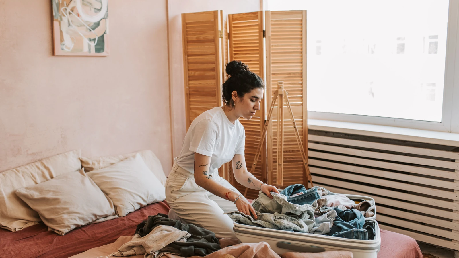 Donna che prepara la valigia in una camera da letto accogliente, preparando per viaggiare. Atmosfera rilassata e intima.