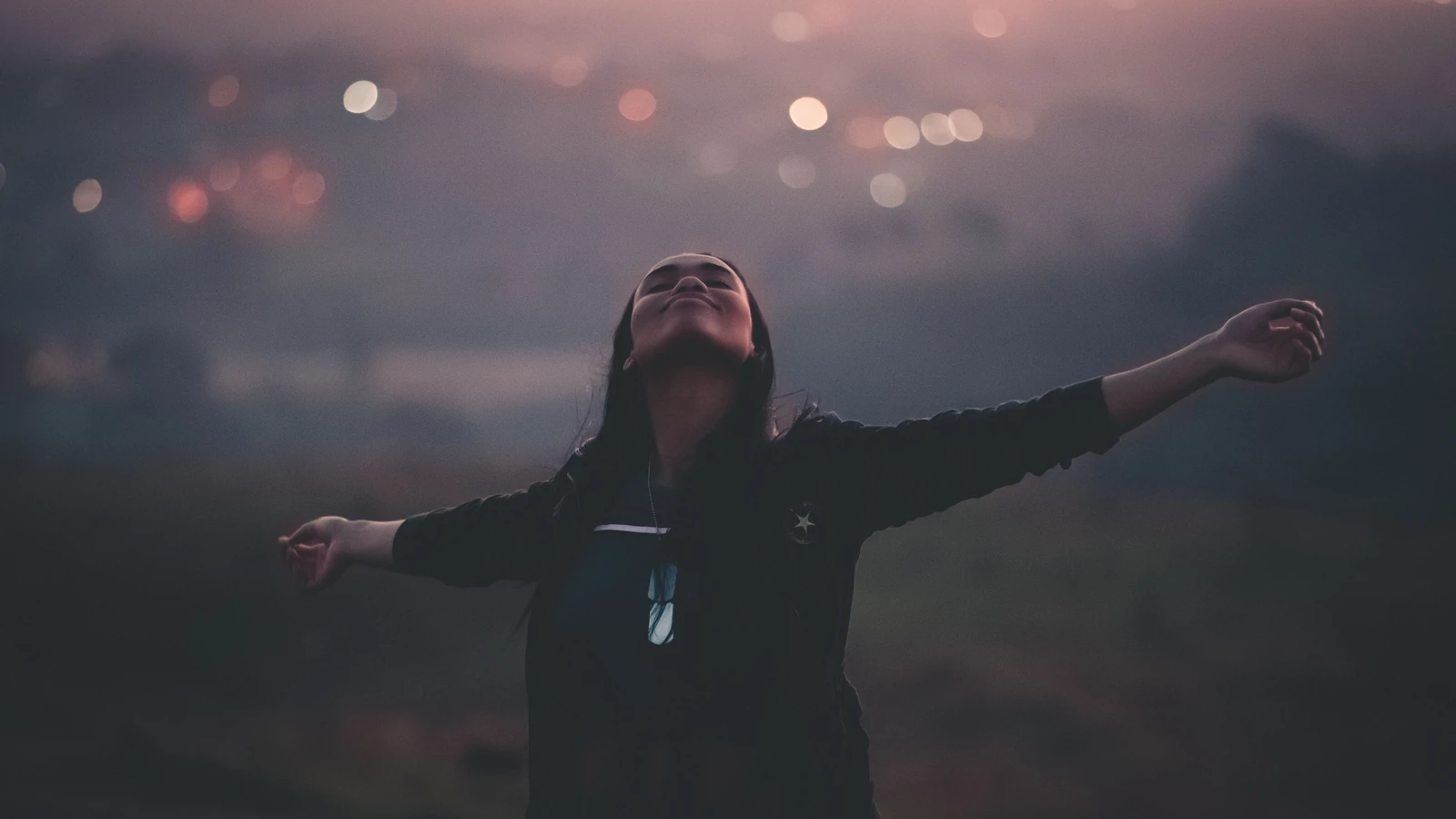 Una donna si gode un momento di libertà e tranquillità in un ambiente esterno sereno al tramonto.