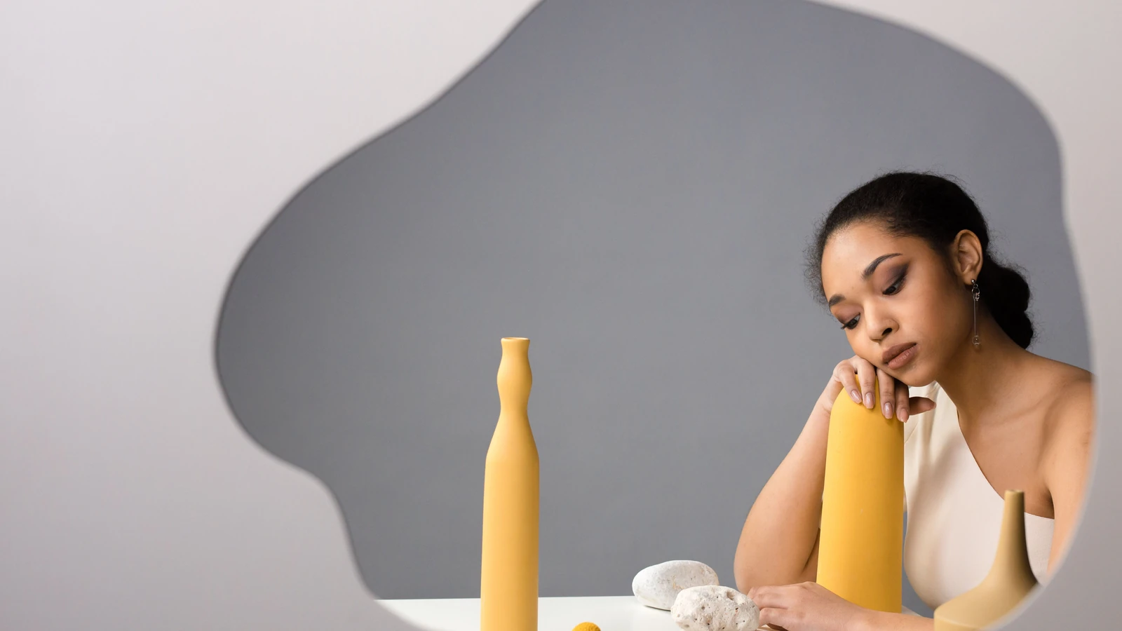 Ritratto di una donna in un ambiente moderno con ceramiche gialle e decorazioni minimaliste.