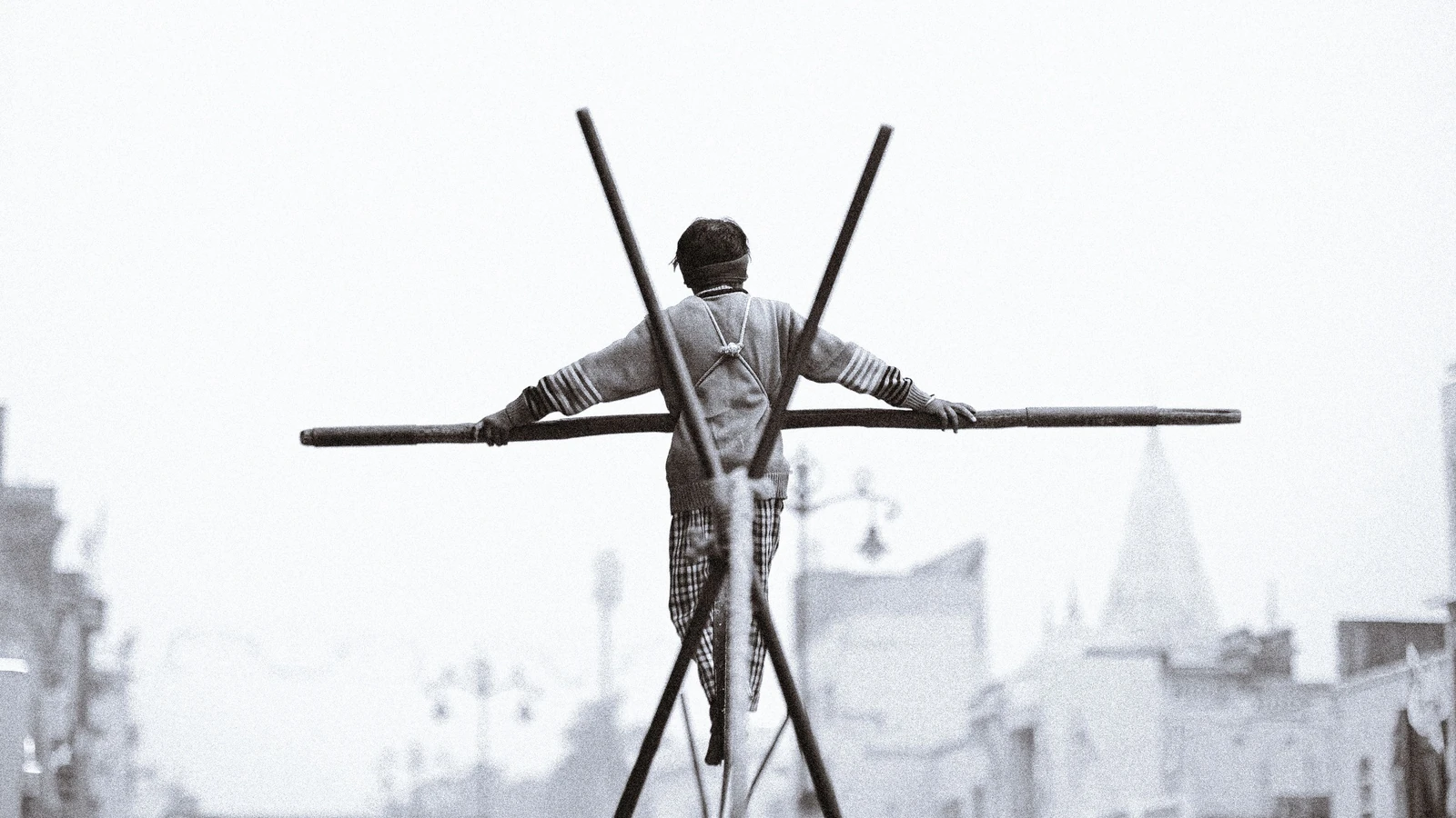 Una scena drammatica di un uomo in equilibrio su una fune ad Ayodhya, che cattura lo sfondo urbano e la tradizionale esibizione di strada.