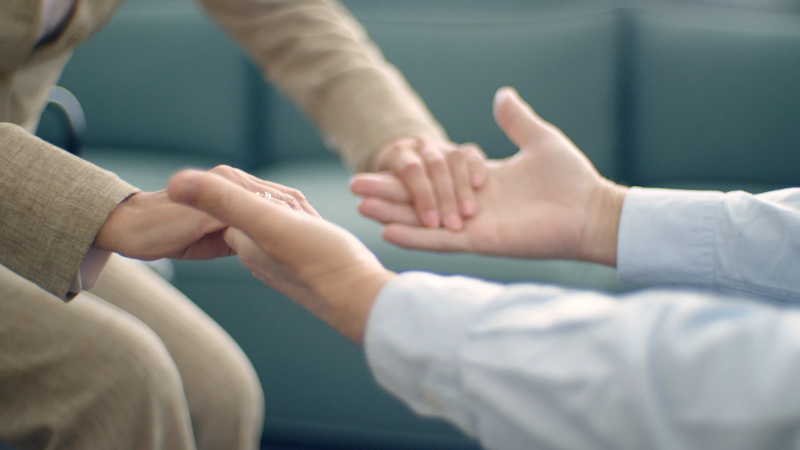 Primo piano di due persone che si tengono per mano, simboleggiando supporto e compassione in un ambiente tranquillo.