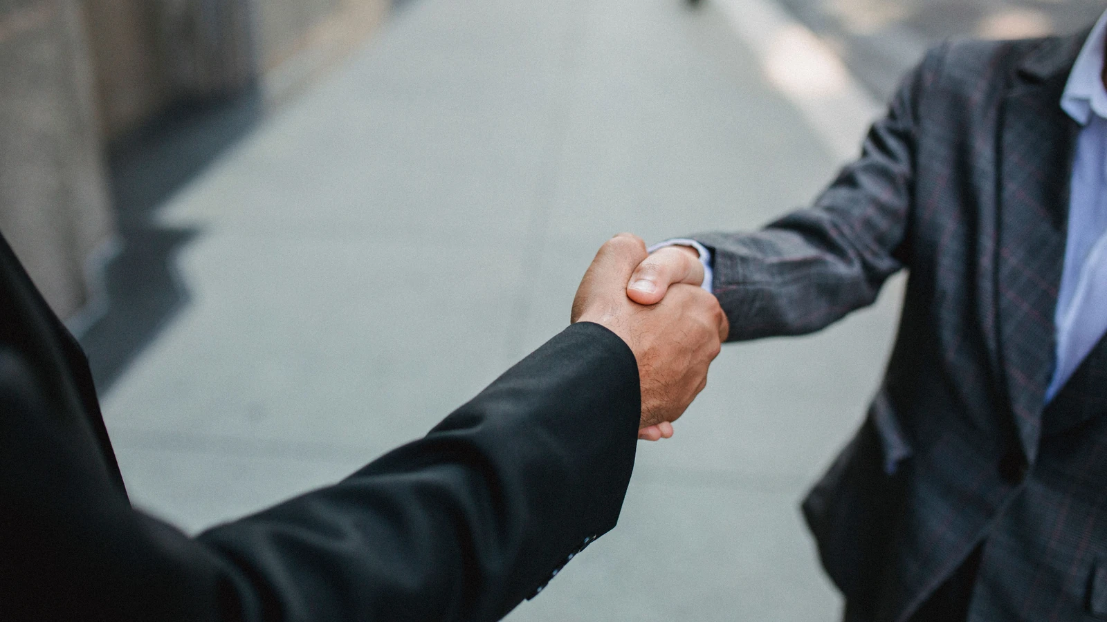 Primo piano di due uomini d'affari che si stringono la mano all'esterno, simboleggiando partnership e accordo.
