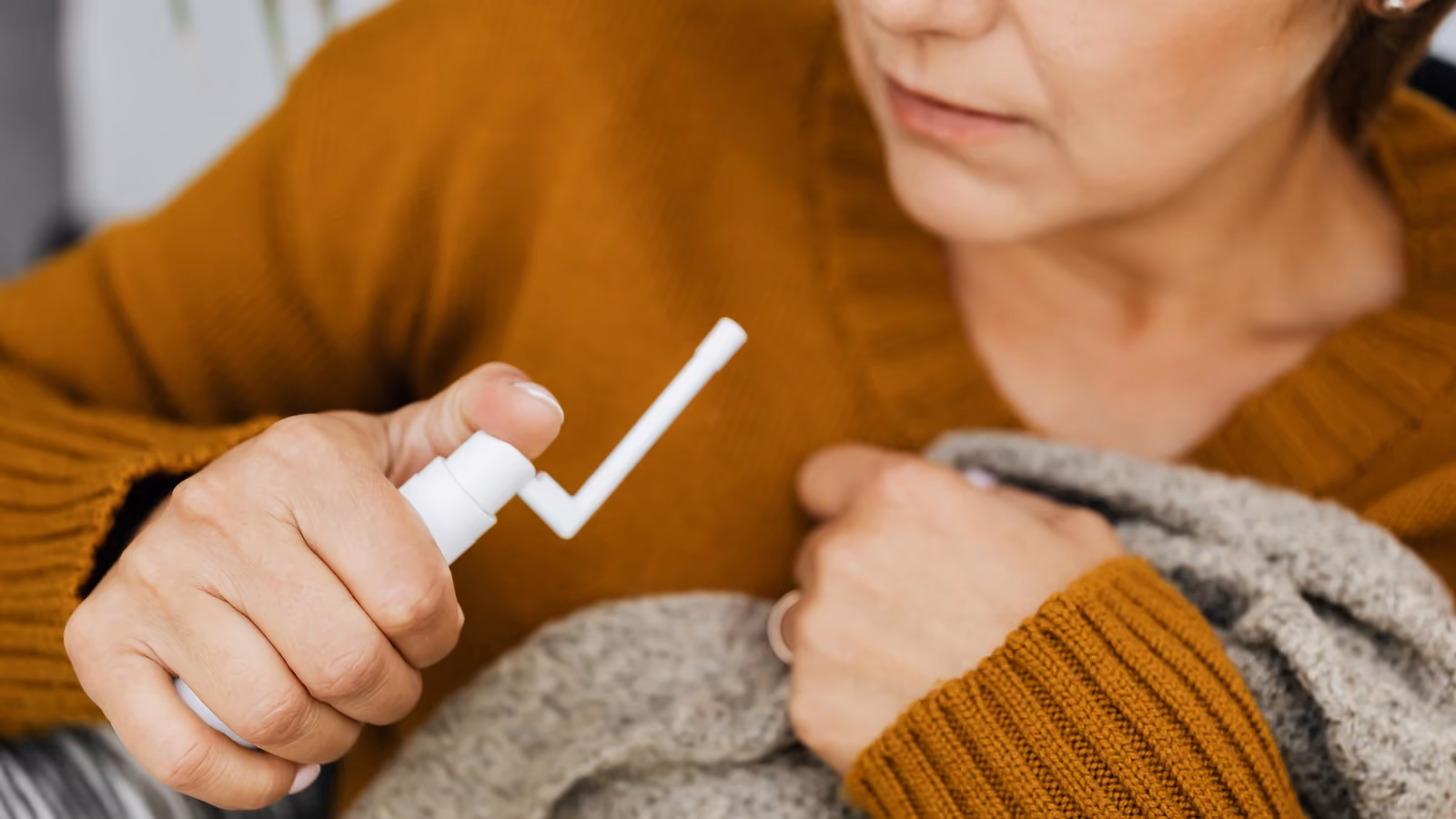 Donna adulta che utilizza uno spray orale per il sollievo in casa, avvolta in un comodo maglione. — https://kaboompics.com/ – Pexels