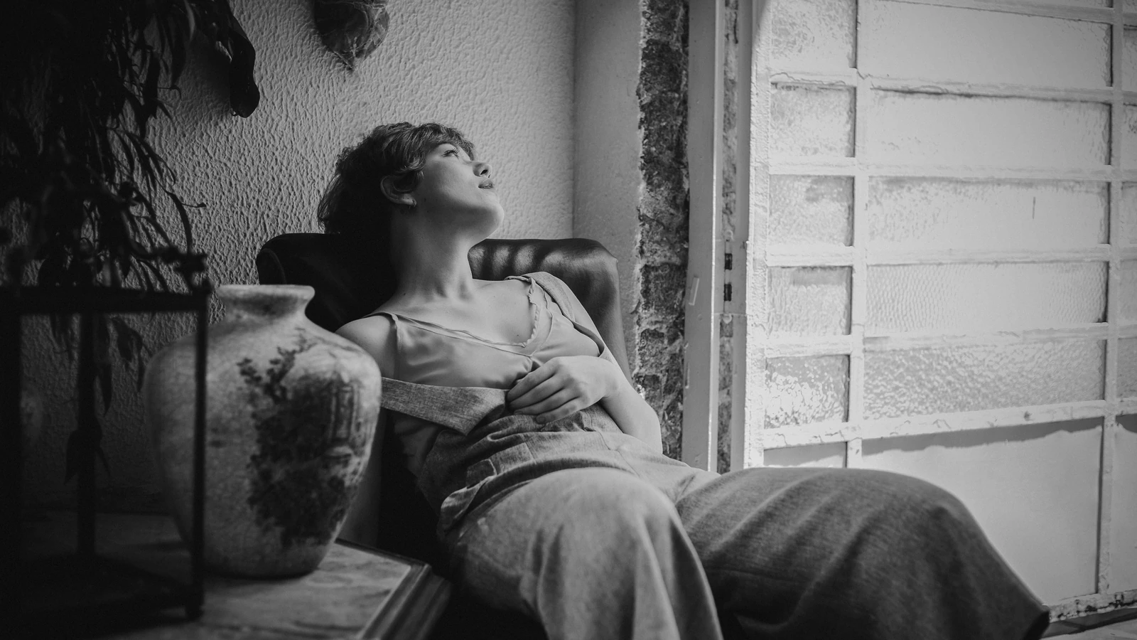 Ritratto artistico in bianco e nero di una donna distesa in un ambiente interno con un'espressione serena.