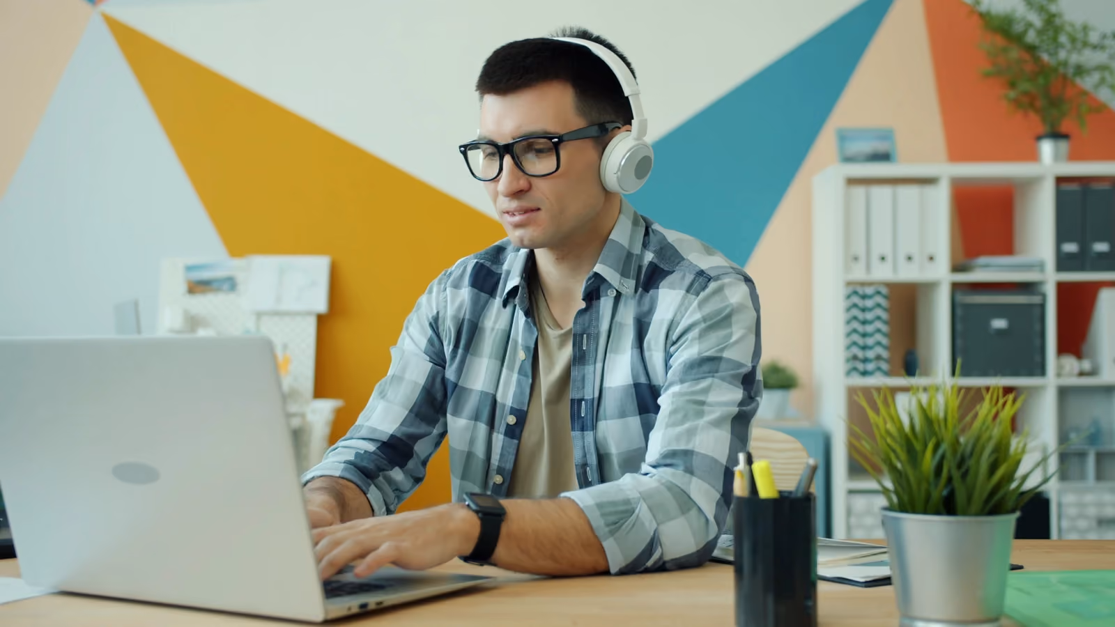 Giovane uomo concentrato sul lavoro con laptop e cuffie in un ufficio moderno ed elegante. — Vitaly Gariev – Pexels