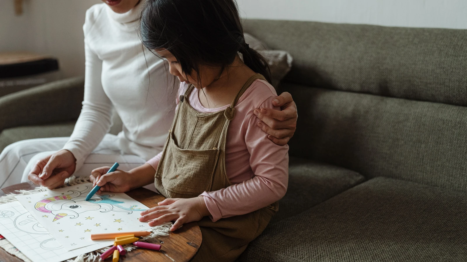 Una madre aiuta sua figlia con un disegno colorato a casa, favorendo la creatività e il legame.