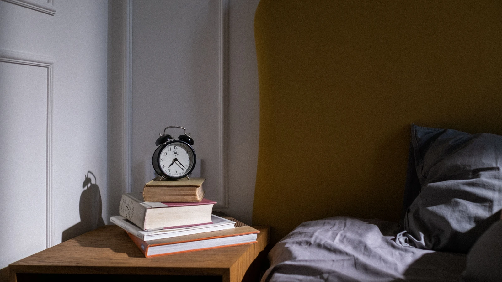 Una camera da letto accogliente con libri e una sveglia sul comodino accanto al letto.