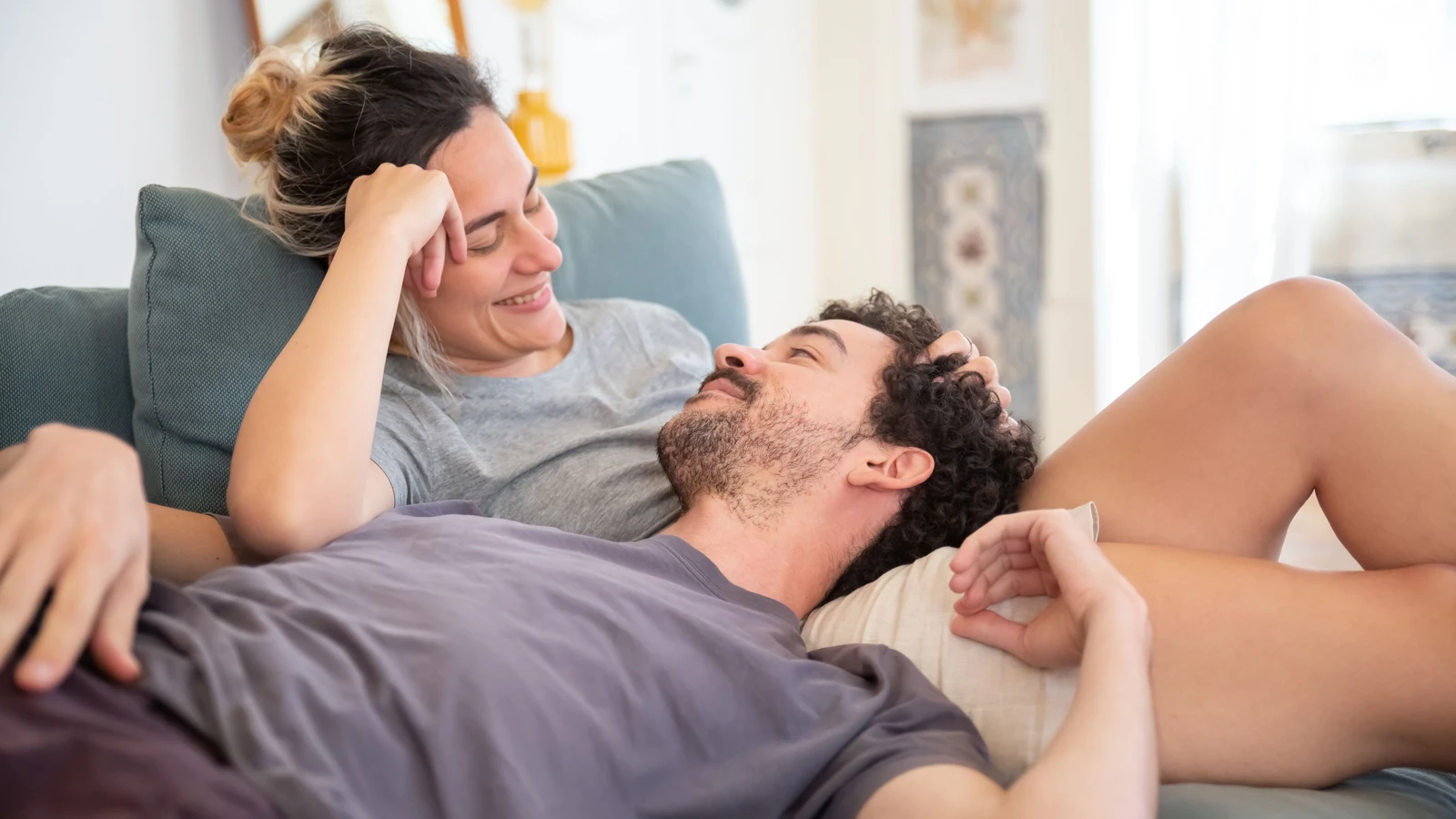 Una coppia innamorata si gode un momento di relax a casa, mostrando affetto e comfort.