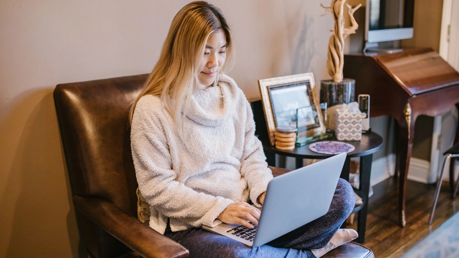 Donna seduta su una sedia con un laptop, che gode di un accogliente ambiente di home office.