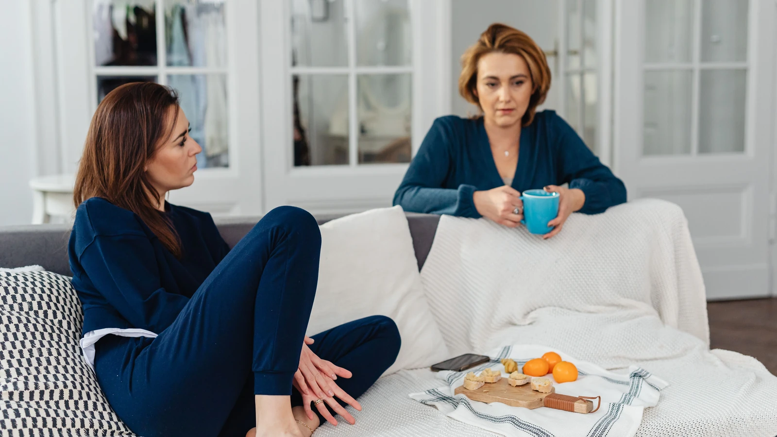 Due donne che godono di caffè e snack mentre si rilassano in un ambiente domestico accogliente.