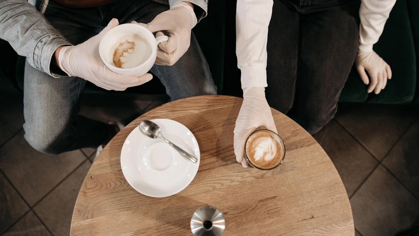 Vista a volo d'uccello di un barista che serve cappuccini con i guanti durante il giorno.