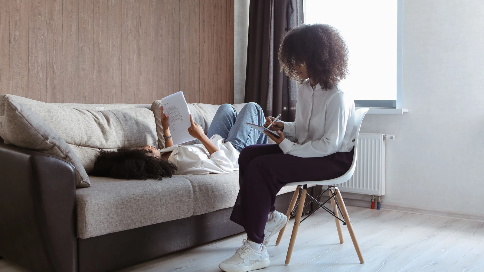 Due donne con capelli afro in seduta di terapia, sedute al chiuso per favorire comunicazione e benessere.