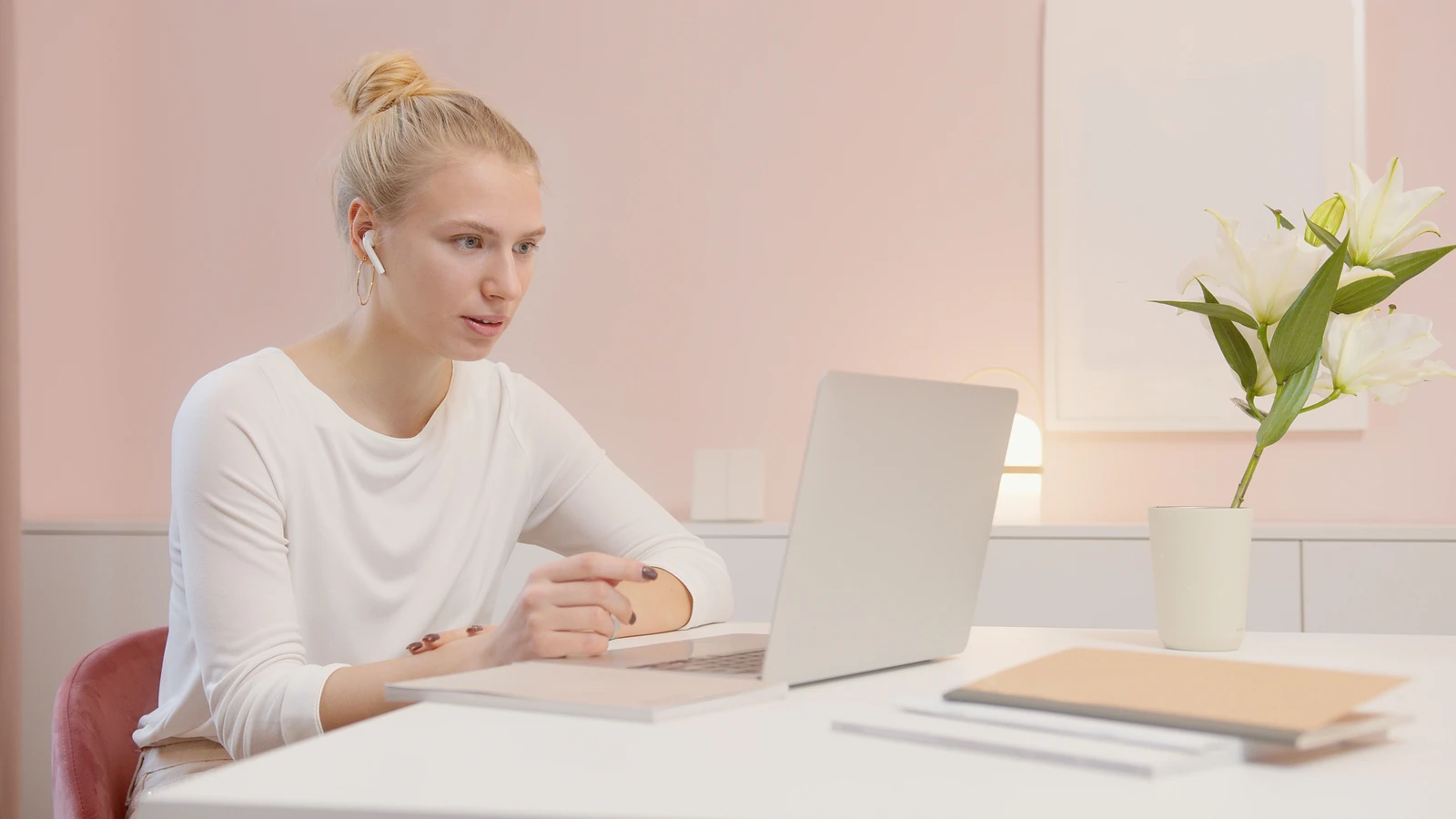 Donna concentrata in un ufficio moderno che utilizza un laptop con AirPods, circondata da un arredamento minimalista.