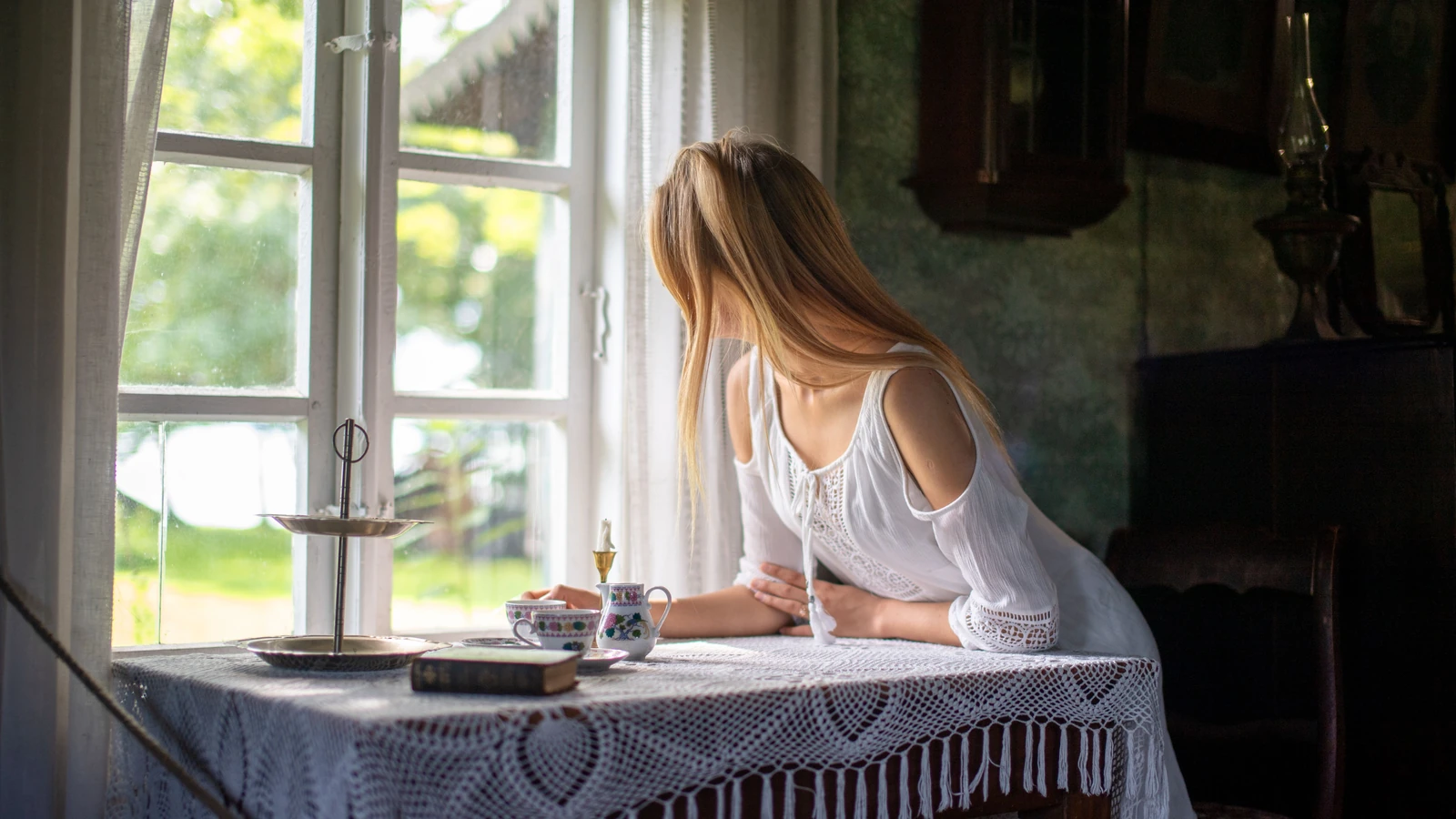 Una donna in abito bianco contempla il suggestivo panorama estivo da un'antica casa estone.