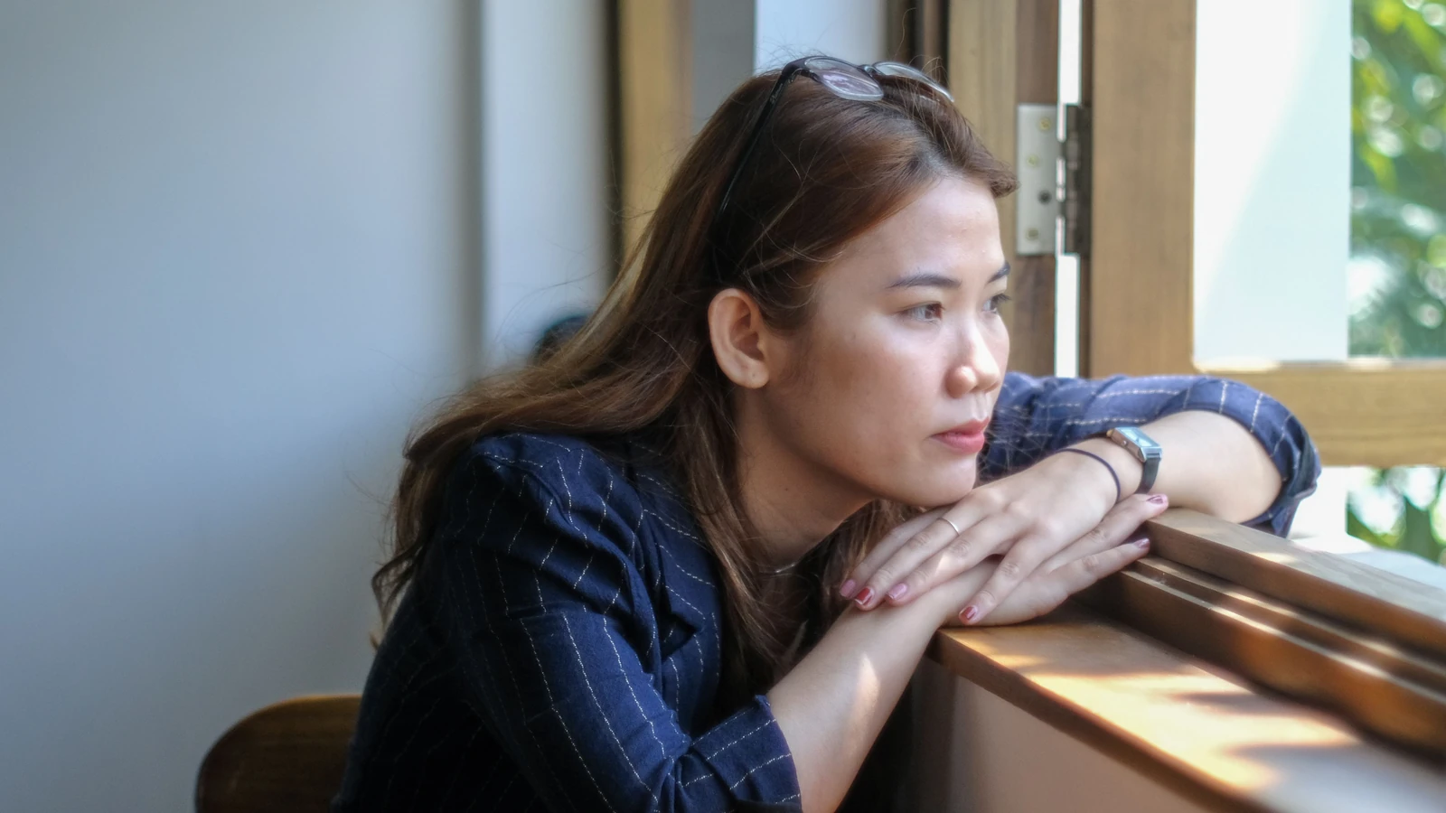 Una donna pensierosa guarda fuori dalla finestra, immortalando un momento di serenità all'interno di un edificio a Da Nang, in Vietnam.