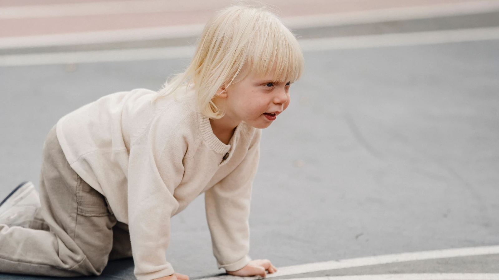Un bambino biondo e felice che gattona in un colorato parco giochi all'aperto, godendosi il tempo libero.