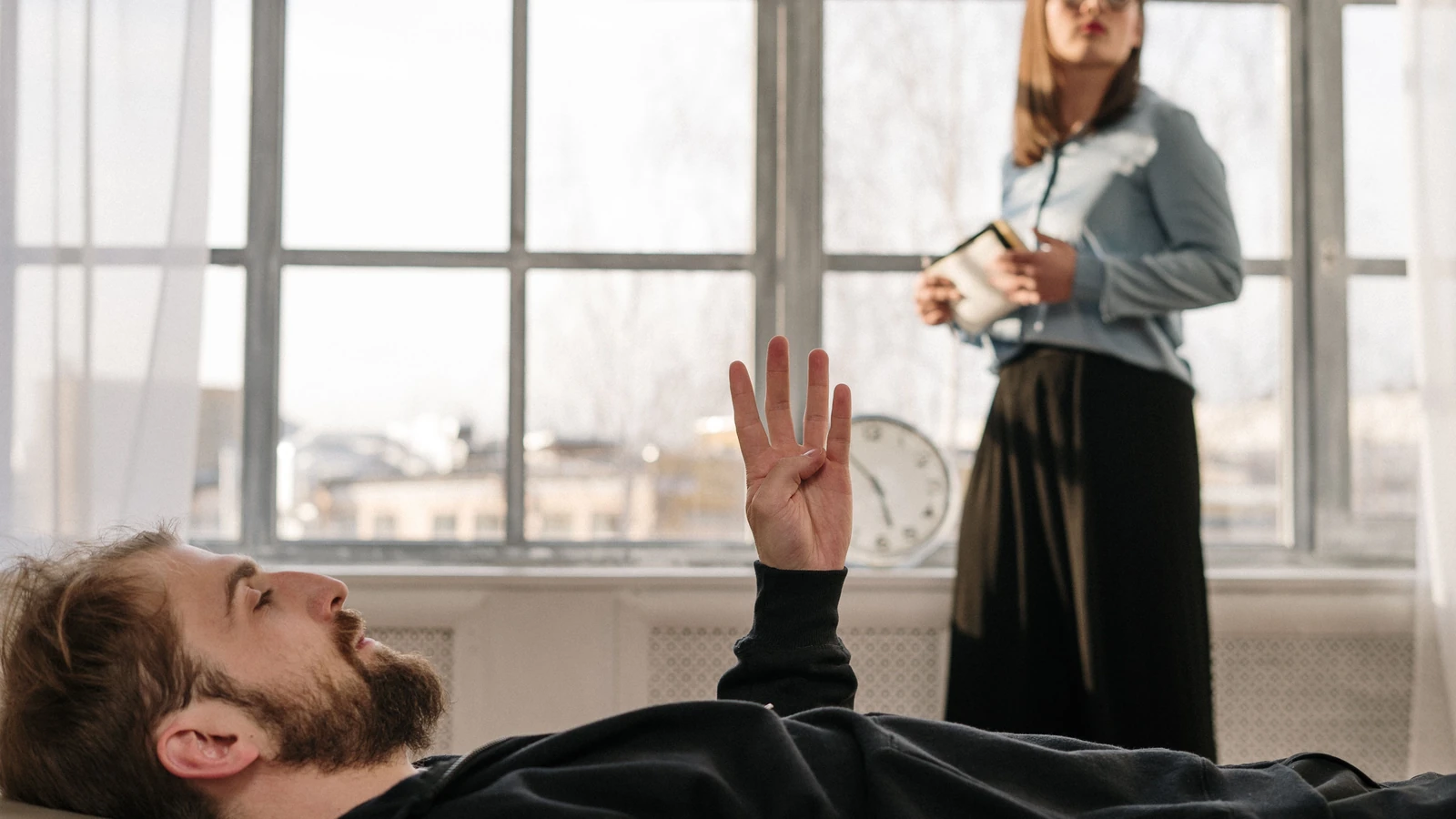 Una sessione di terapia con un paziente maschile e una terapeuta femminile che discutono preoccupazioni in un ufficio luminoso.