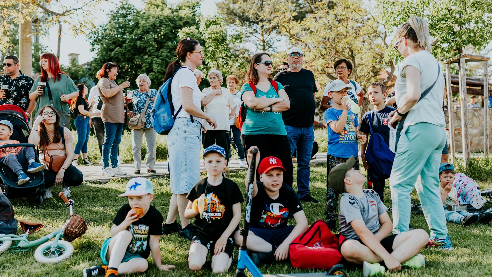 Un gruppo diversificato di famiglie e bambini che si divertono a un evento all'aperto in una giornata di sole in un parco.