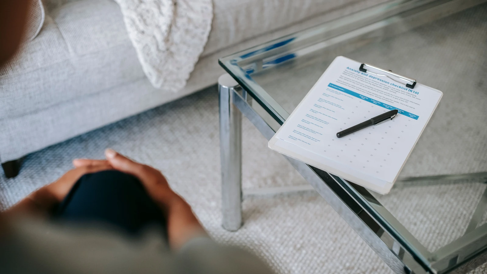 Ambiente per una sessione di terapia con clipboard e modulo di valutazione dell'ansia su tavolo di vetro.