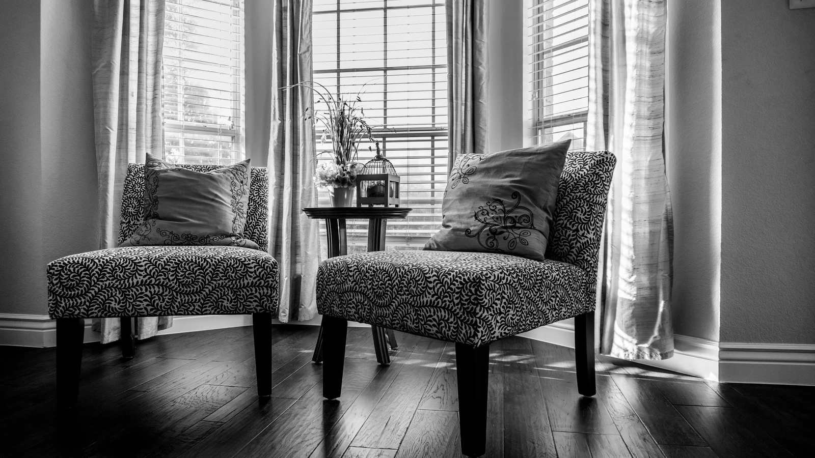 Elegante interno domestico in bianco e nero con sedie fantasie e un tavolo vicino alla finestra.
