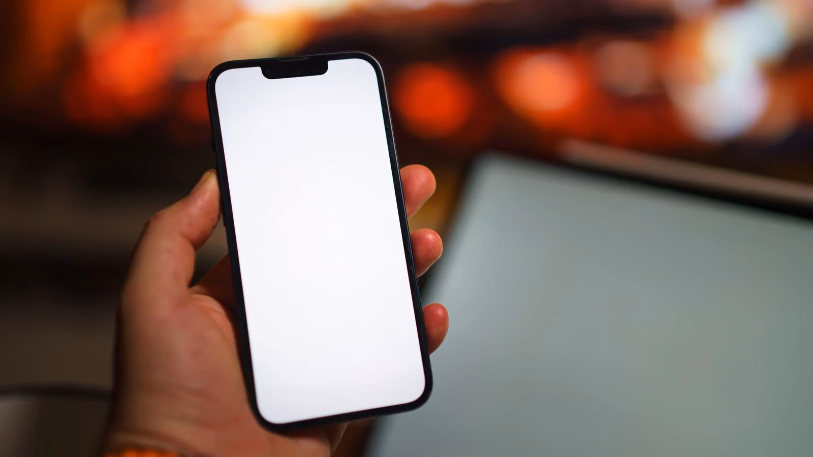 Schermo vuoto di uno smartphone tenuto in mano in un ambiente interno caldo e accogliente, ideale per mock-up — Jakub Zerdzicki – Pexels