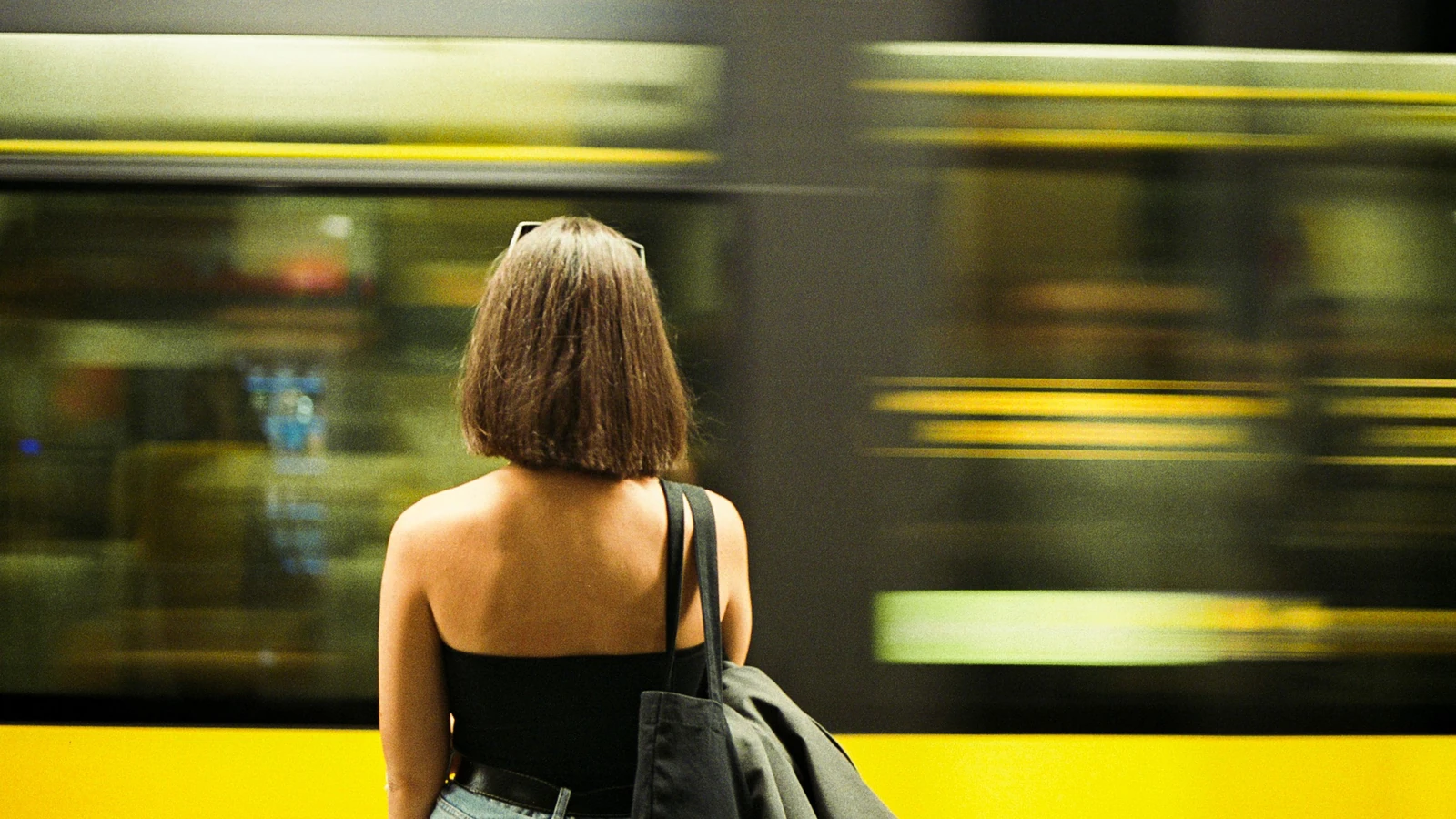 Vista posteriore di una donna in una vivace stazione della metro a Porto, Portogallo, mentre un treno sfreccia.