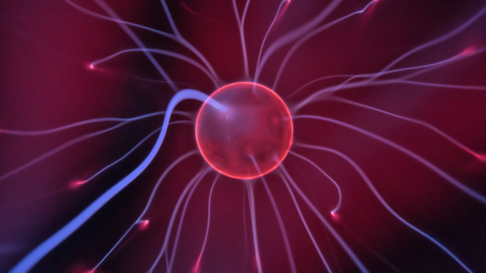 Primo piano di una sfera di plasma che brilla con correnti elettriche colorate che si estendono verso l'esterno.